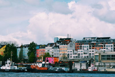 Buildings by river against sky in city