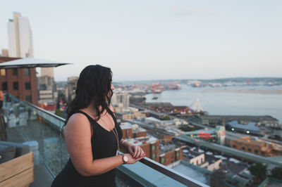 Woman standing by railing against sky