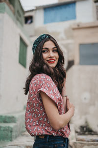 Portrait of smiling young woman standing against building