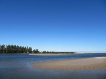 Scenic view of beach against clear blue sky