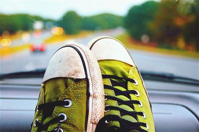 Close-up of shoes on road by car on street