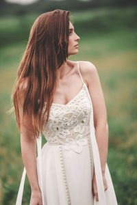 Young woman looking away while standing outdoors