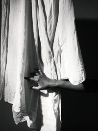 Cropped hand of woman touching curtain at home