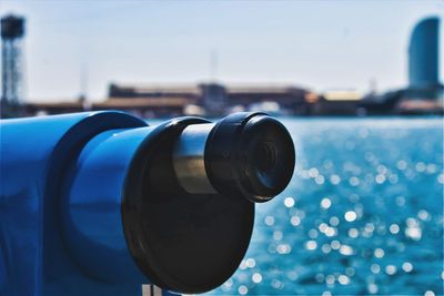 Close-up of coin-operated binoculars by sea against clear blue sky