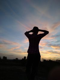 Silhouette man standing on field against sky during sunset