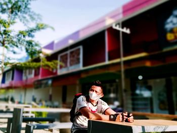 Young woman sitting on table against built structure