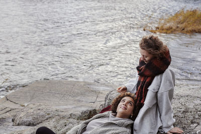 Female couple relaxing on rocks by lake