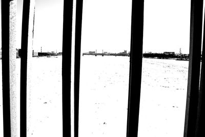 Silhouette building by sea against clear sky seen through glass window