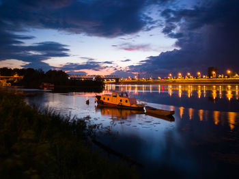 Boats moored in lake against sky at sunset