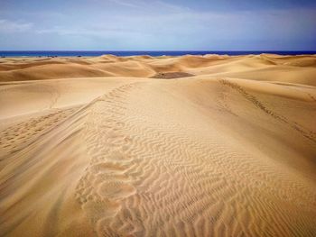 Scenic view of sand dune on beach against sky