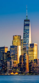 Illuminated buildings at waterfront against clear sky