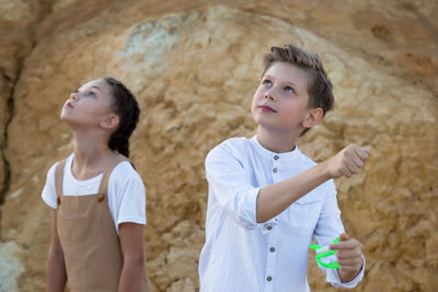 Children watching the flight a kite with interest looking into the sky.