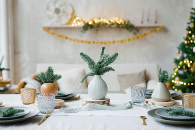 Stylish and trendy design of a festive table set for a family dinner. vases with spruce 