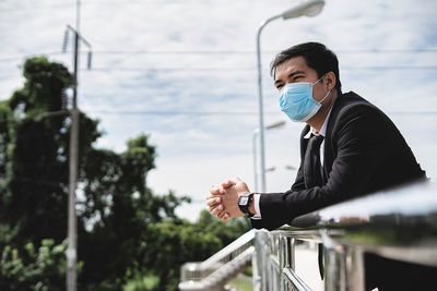 Asian businessman holding briefcase walking on overpass looking outside