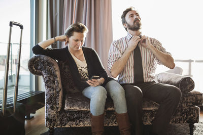 Business couple relaxing on chaise longue in hotel room