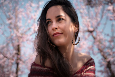 Portrait of a beautiful young woman against cherry blossoms
