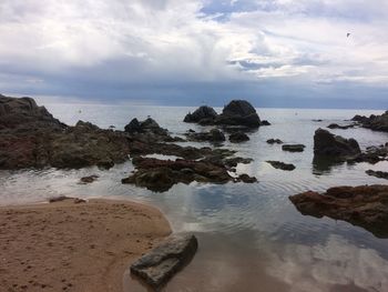 Scenic view of rocks on beach against sky