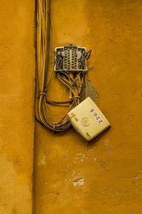 Close-up of broken fuse box on yellow wall