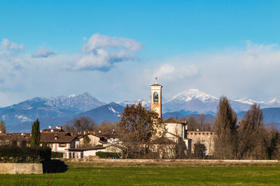 Built structure on field by buildings against sky