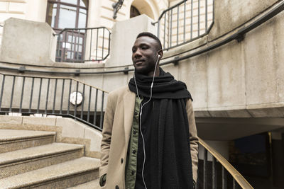 Man listening music while standing in city