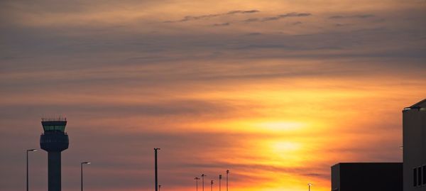 Low angle view of street lights against orange sky