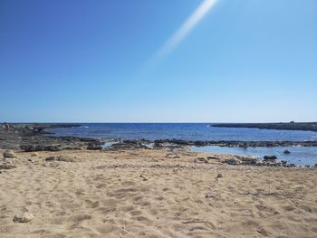 Scenic view of beach against clear blue sky