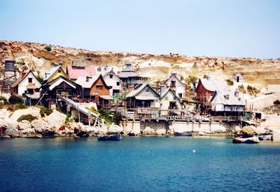 Houses by sea against clear sky