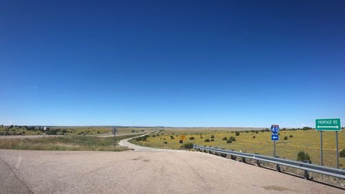 Road passing through landscape against clear blue sky