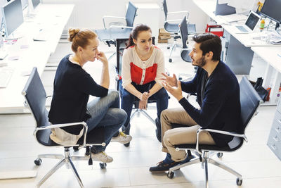 Mid adult businessman with colleagues having discussion in office