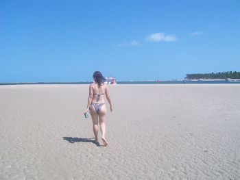 Rear view full length of woman in bikini at sandy beach