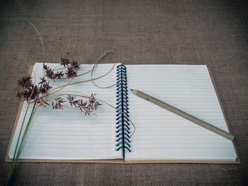 High angle view of pencil and open book on burlap