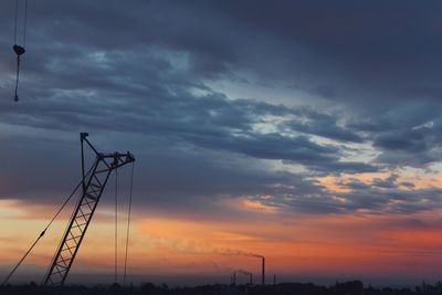 Low angle view of silhouette electricity pylon against dramatic sky
