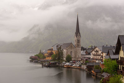 Buildings at waterfront in town against cloudy sky