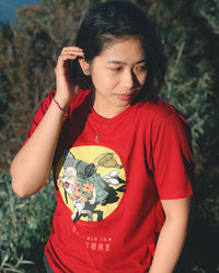 Portrait of young woman standing against plants