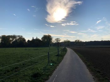 Road amidst field against sky