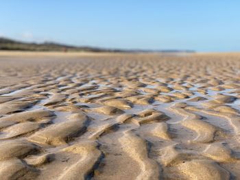 Surface level of sand on beach against clear sky