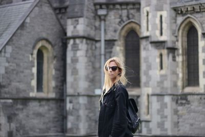 Portrait of young woman standing against building