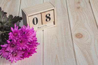 Wooden march 8 calendar, next to purple flowers on wooden table. selective focus. happy womans day.