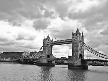 Bridge over river against cloudy sky