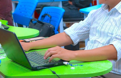 Midsection of businessman using laptop on table