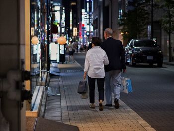 Rear view of man walking on street at night