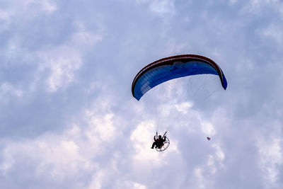 Low angle view of person paragliding against sky