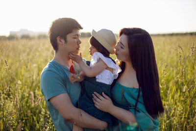 Korean family mom and father with a girl child daughter with candy lying on a green field in summer