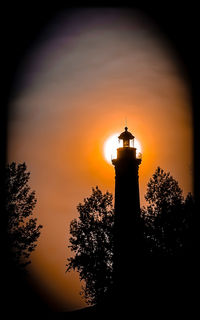 Low angle view of silhouette lighthouse against sky during sunset
