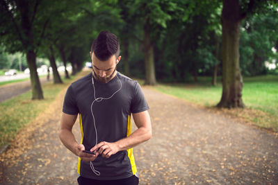 Athlete listening to music through mobile phone in park