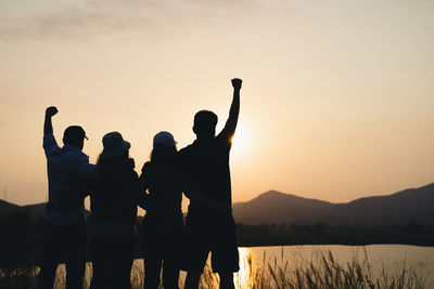 Silhouette people standing against sky during sunset