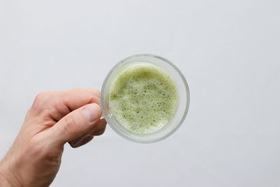 High angle view of hand holding glass against white background