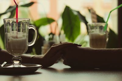 Cropped image of couple holding hands on table at cafe