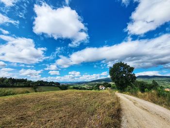 Dirt road along landscape and against sky