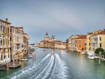 Canal amidst buildings against sky in city